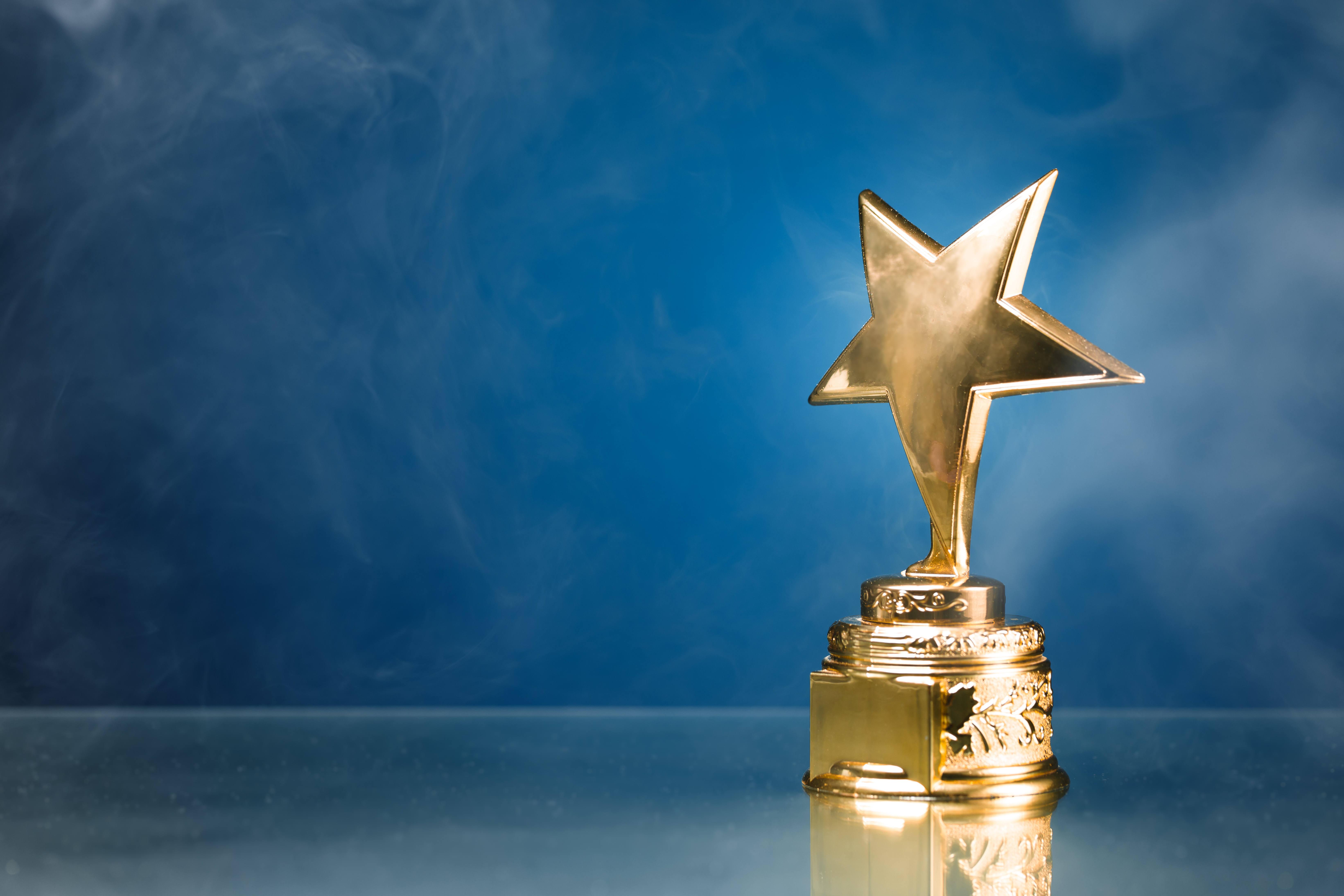 Gold,Star,Trophy,In,Smoke,,Blue,Background